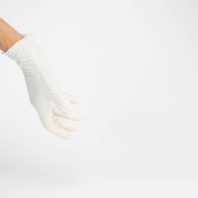A professional moving technician in a beige uniform with a black wristband is shown using a handheld laser device for a skin treatment or medical procedure on a person's forearm, which is covered with